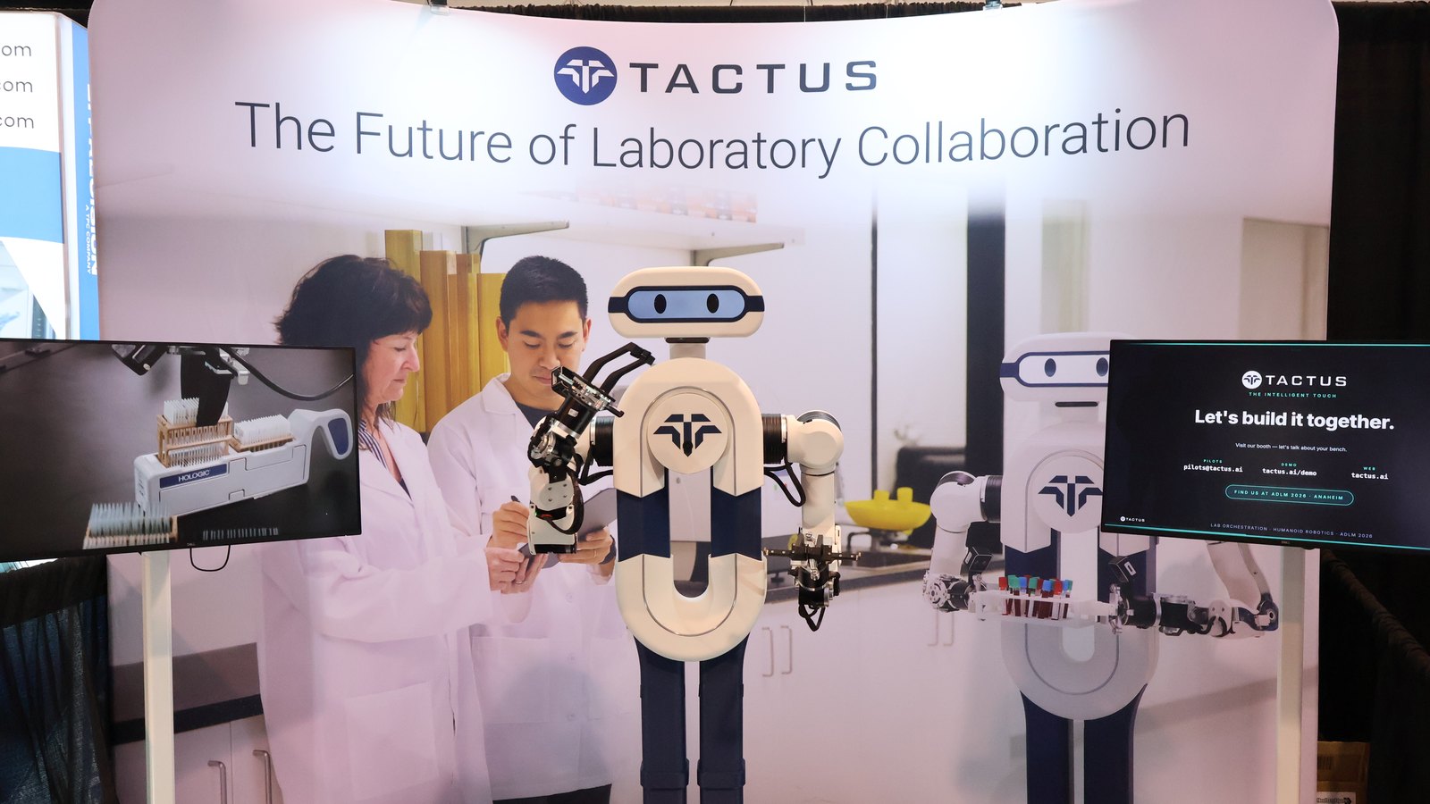 The Tactus AI booth at ADLM 2026, with Elsie the humanoid lab assistant standing in front of the Tactus banner while two laboratory scientists work beside her