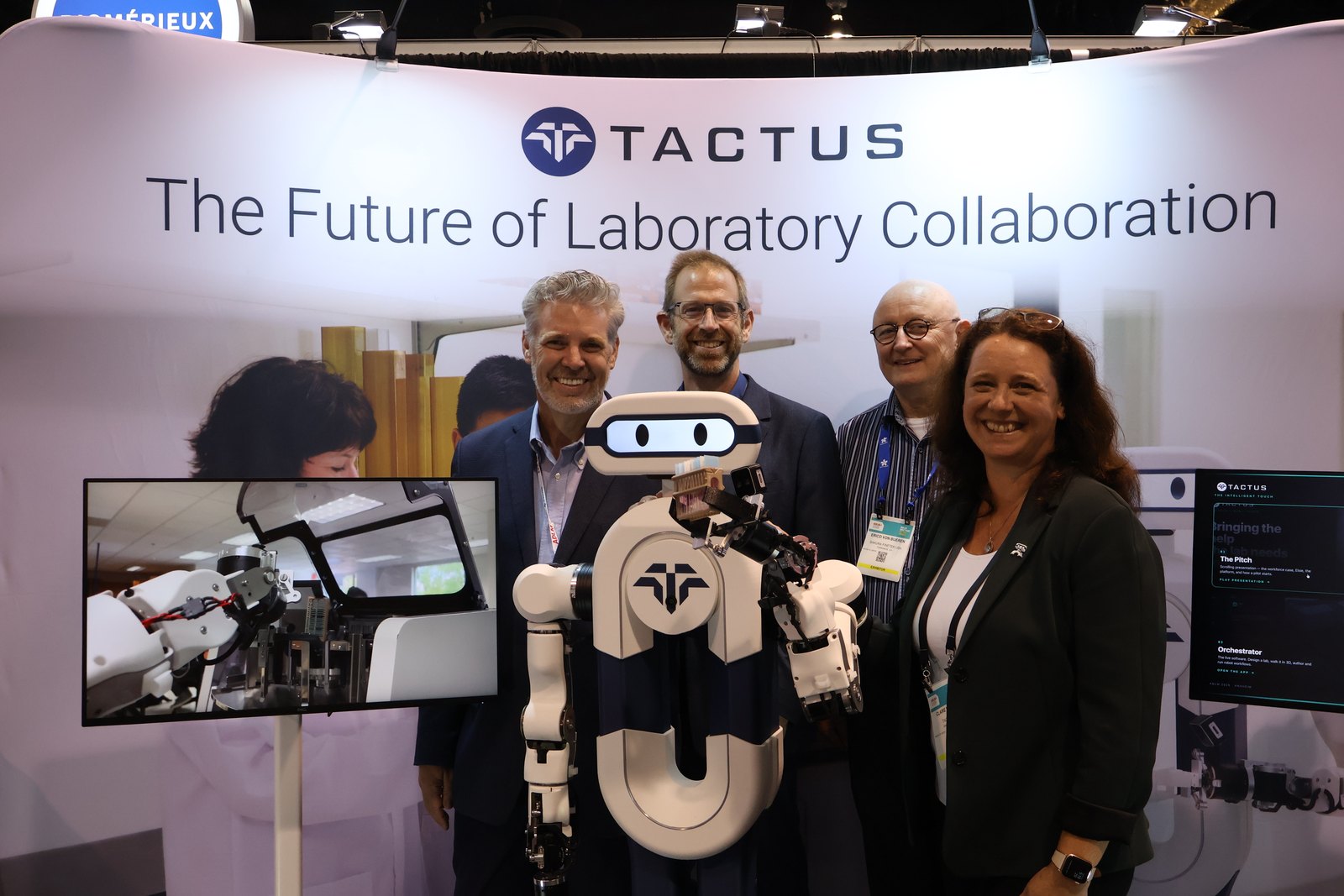 Visitors to the Tactus AI booth at ADLM 2026 stand with Elsie, the humanoid lab assistant, in front of the Tactus banner