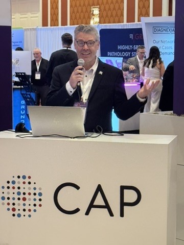 Michael Quick speaks into a microphone at the CAP podium during his Innovation Hub talk