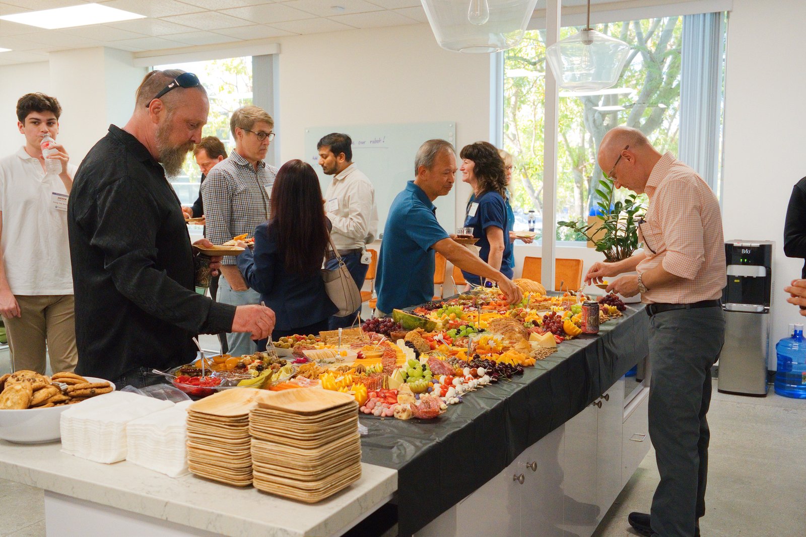Guests gather around a food spread at the Tactus AI Open House on the San Diego campus